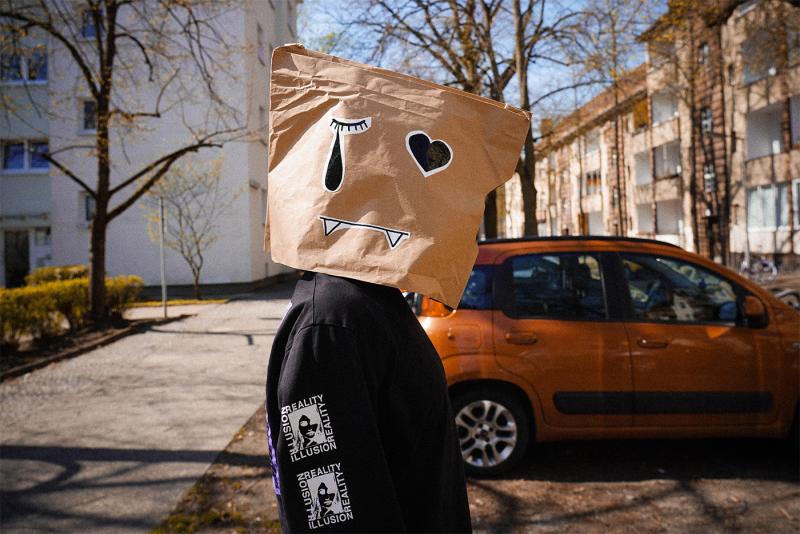 Eine Person auf der Straße trägt eine selbstgemachte Papiermaske