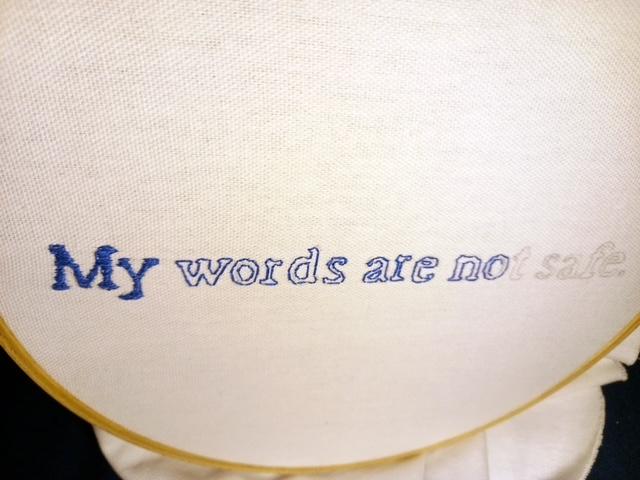 Blue embrodiered text on cream fabric which reads; My words are not safe.