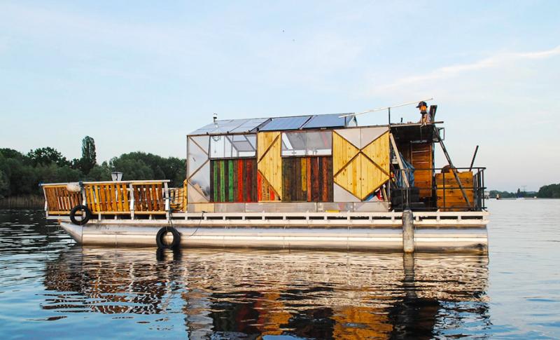 Ein aus Recyclingmaterialien gebautes buntes Plattform-Boot schwimmt auf der Spree.