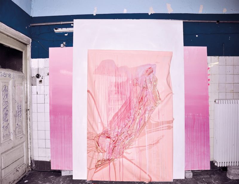 In einem weiß gefließtem Raum, stehen neben dessen Eingangstür einige großdimensionale Bilder gestapelt, ganz vorne ein rosa pastellfarbenes  abstraktes Ölgemälde, in der Größe der Tür, etwas verformt, dreidimensional mit pinken, roten und weißen Formen. 