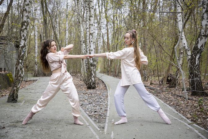 Two dancers hold hands at a path fork.