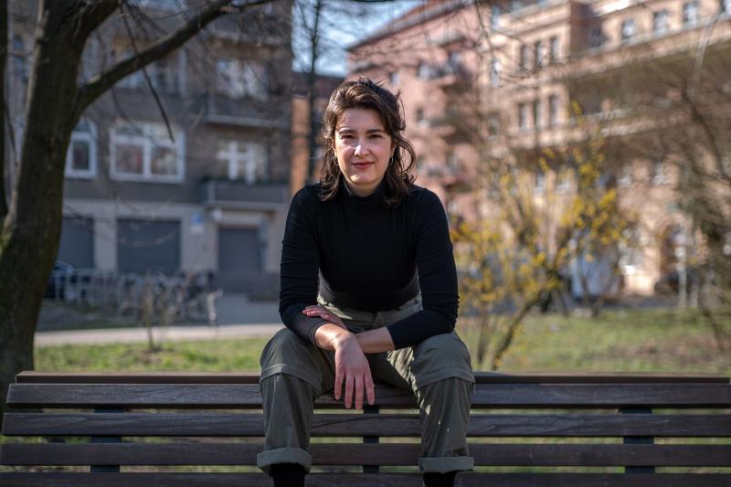 Portraitaufnahme von Sophia M. Estel, auf der Rückenlehne einer Parkbank sitzend.