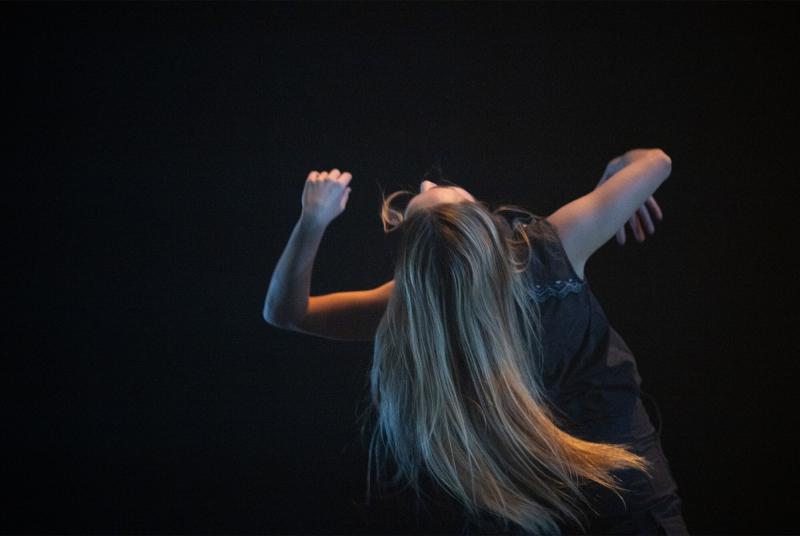 A dancer with long hair arches back.