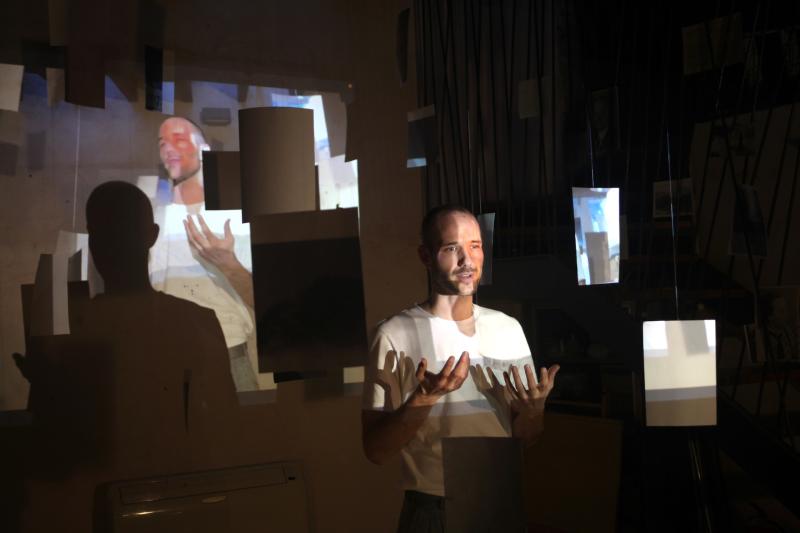 Performer gestikuliert in Videoprojektion