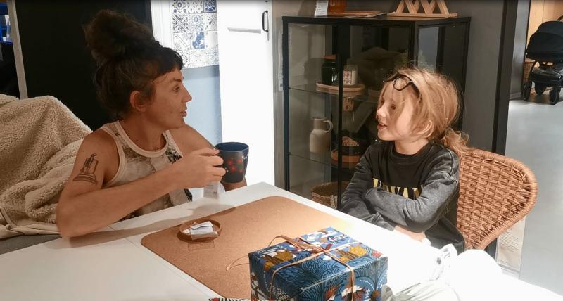 Filmstill. Einer Frau und eines Kindes, die in einer Modellküche von Ikea sitzen