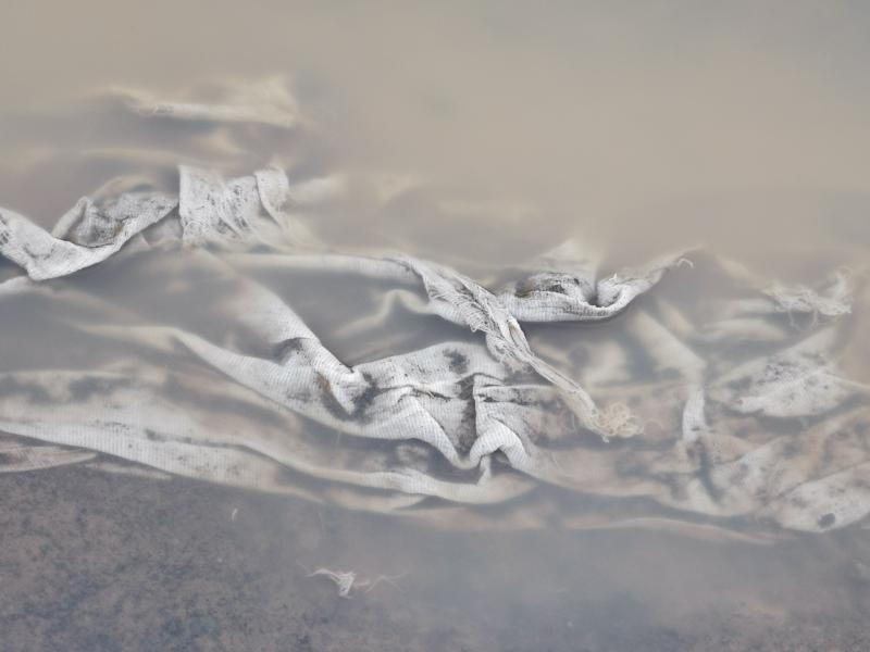 ein grobes Tuch in schlammiges Wasser getaucht, es wirft Wellen