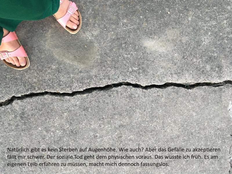 ein asphaltierter Weg, zwei Füße vor einem großen Spalt