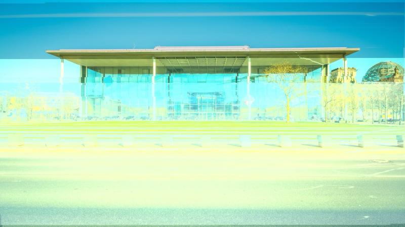 Verfremdete Außenansicht des Paul-Löbe-Hauses in Berlin. Die Architektur erscheint durch digitale Glitch-Artefakte verzerrt: Farben verschoben, Strukturen fragmentiert, horizontale Linien stören die Bildfläche. Das Gebäude wirkt entleert, synthetisch, beinahe transparent. Eine ironisch-kritische Anspielung auf die Erzählung von Berlin als Bühne der Simulation.