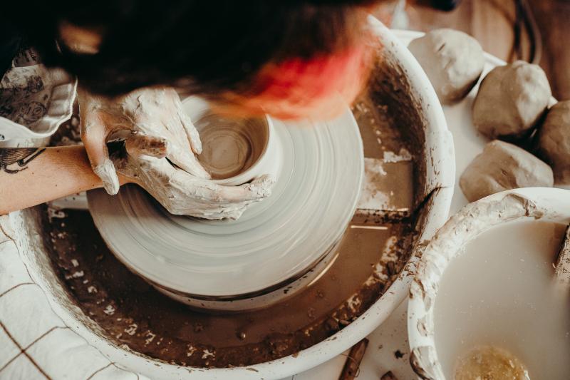 Hands throwing clay on the wheel, perspective from above