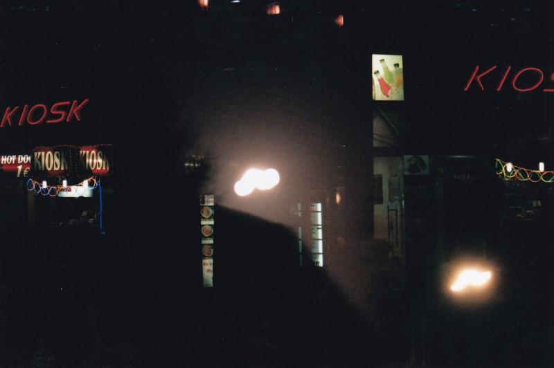 Doppelt belichtetes Analogfoto einer Straßenszene mit Leuchttafeln, Neon- und Straßenlichtern bei Nacht