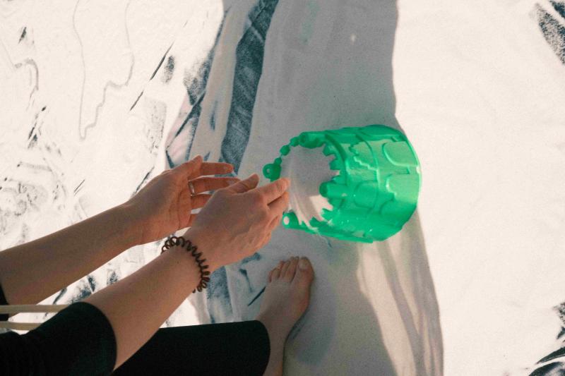 Zwei Hände agieren mit Sand und Sandspielzeug.