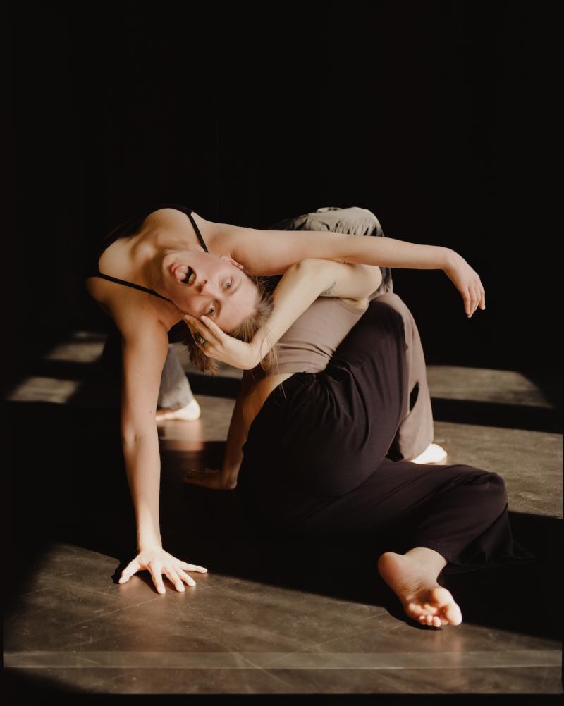 one person hold the head of another, leaning back and sticking out their tongue