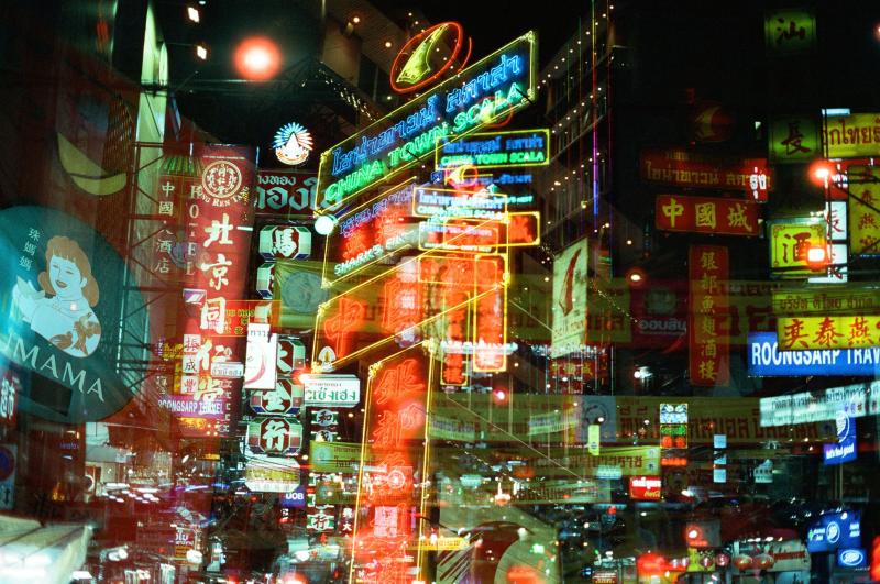 Das mehrfach belichtete Bild zeigt eine Straße mit Neonlichtern und chinesischen Schriften. Es herrscht Chaos.