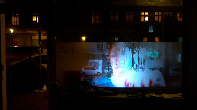 Zu sehen ist eine Projektion im Schaufenster bei Nacht. 