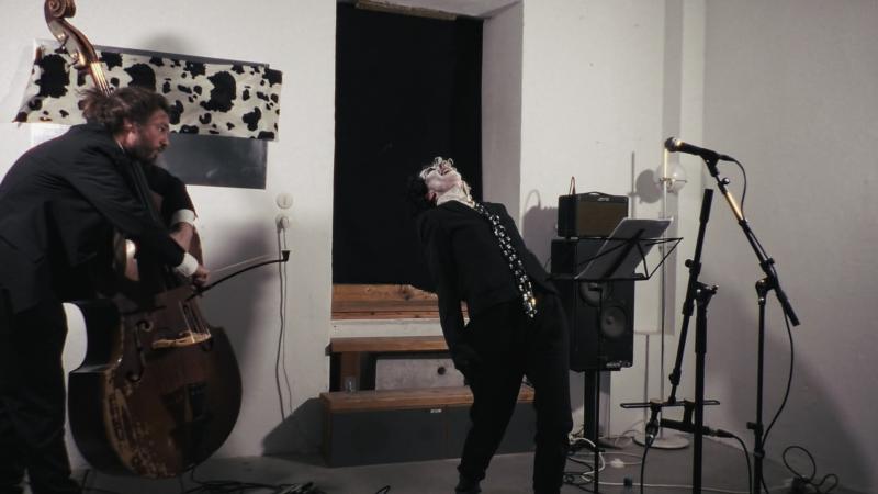 Kontrabassist spielend, während die Performerin sich weit nach hinten beugt; das Bild vermittelt die energetische Intensität der Performance „The Burrow Project"