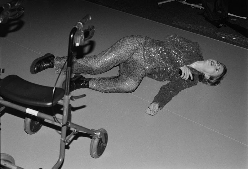 Schwarzweiß-Foto einer Schauspielerin auf dem Boden neben einer kleinen Trittleiter