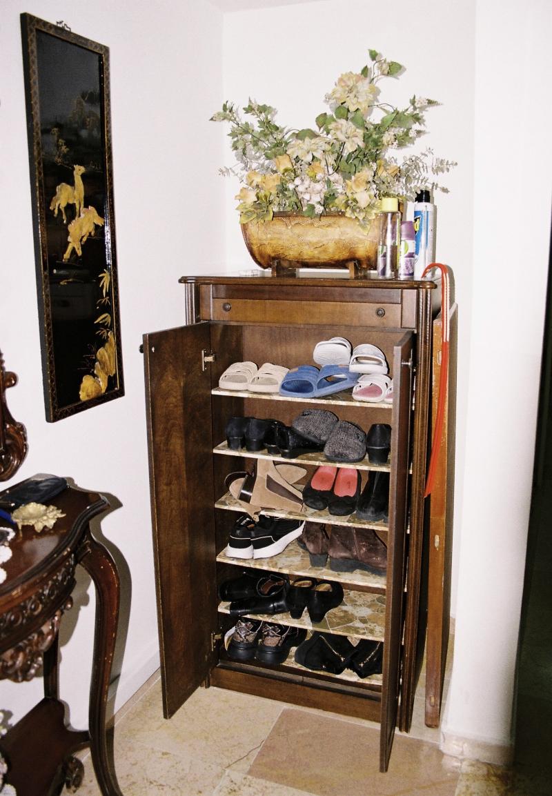 An open shoe closet captured with flash on, representing the daily rhythm of the house and how it used to be.