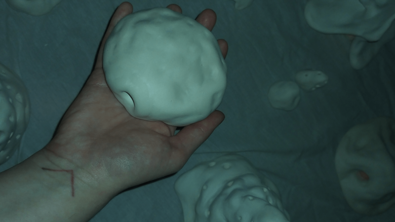 Image of a hand holding a round ceramic object with a subtle warm glow radiating from inside of it, surrounded by other similar objects.