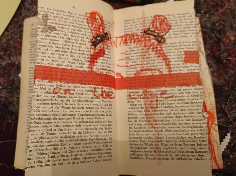 Eine mit roter Tusche bemalte Buchseite, in der Mitte eine rote Linie, darüber ein Kopf, Stirn, Haaransatz und zu kleinen Zöpfen geflochtene Haare. Unter der Linie der Satz: on the edge.