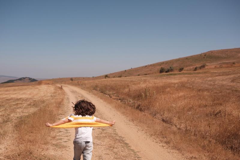 Ein Kind läuft über einen staubigen Weg durch eine weite, offene Landschaft. Zwischen Spiel, Bewegung und Freiheit entsteht ein Bild von Aufbruch, Zukunft und unbeschwerter Gegenwart.