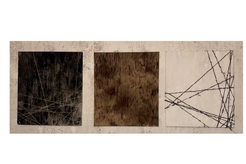 Three abstract paintings installed side by side on a textured wall, connected by crossing threads.