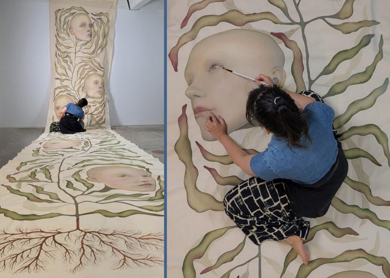 The image shows artist working on the painting in her studio