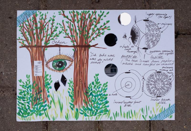 A large eye hangs from two trees. Working sketches to show how you would look into an installation of an eye and see many small mirrors reflecting your image back at you.  Zwischen zwei Bäumen hängt ein großes Auge. Skizzen veranschaulichen den Blick in die Installation: Im Inneren erscheinen zahlreiche kleine Spiegel, die das eigene Bild vielfach reflektieren.