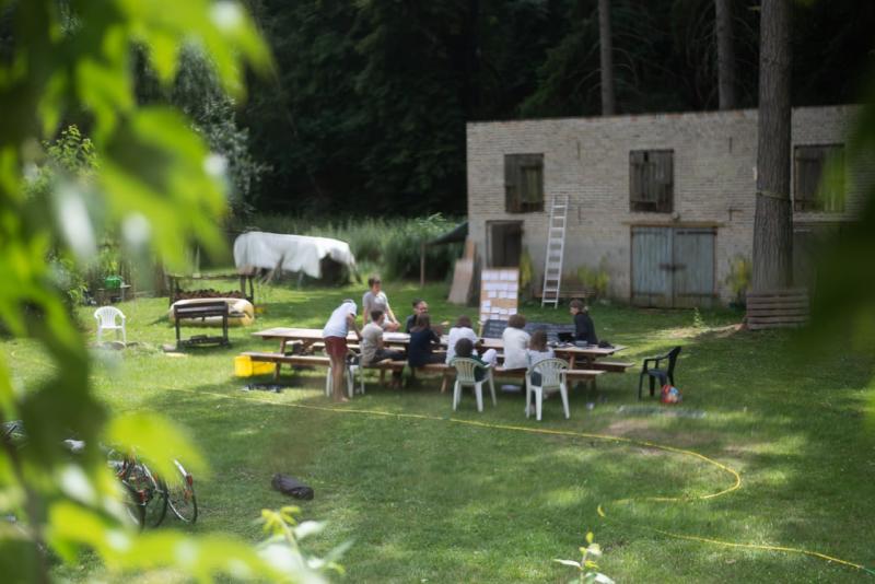 Verschwommenes Foto einer Gruppe, die am Garten um einen Tisch sitzt und sich angeregt unterhält