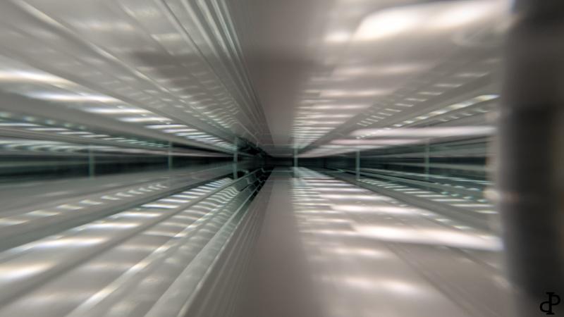 Symmetrische Lichtreflexionen im Inneren einer Glasscheibe erzeugen den Eindruck eines tunnelartigen Raums mit fluchtpunktartiger Perspektive.