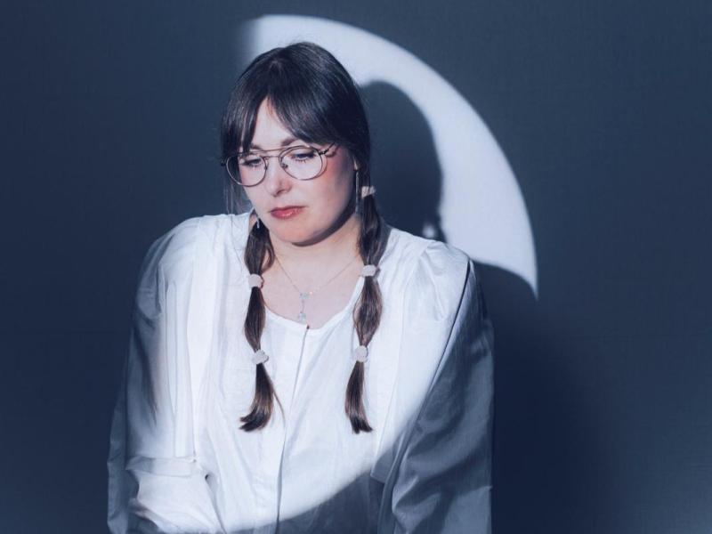 Porträt der Musikerin Freya Arde in einem kleinen Scheinwerferkreis, der einen Halbmond auf ihr Gesicht und ihren Oberkörper malt