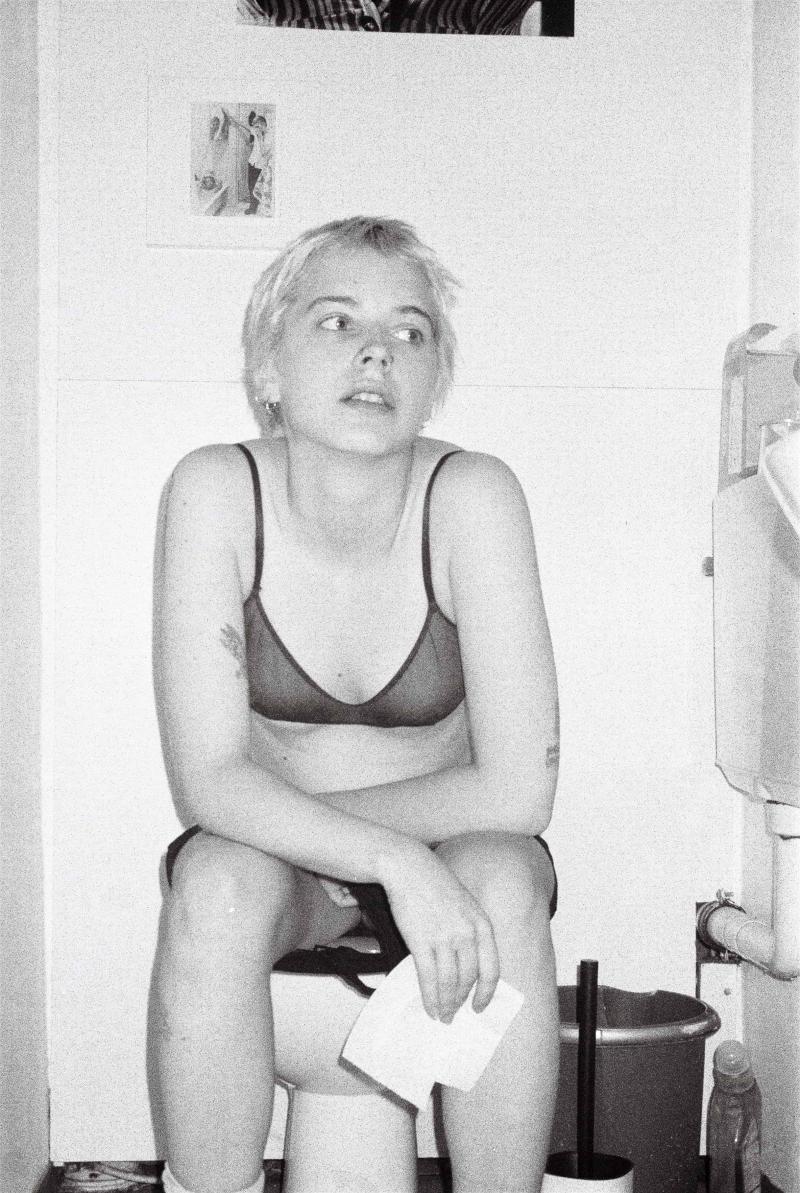 analoges schwarzweiß Foto. Person sitzt auf Toilette und schaut in die Leere
