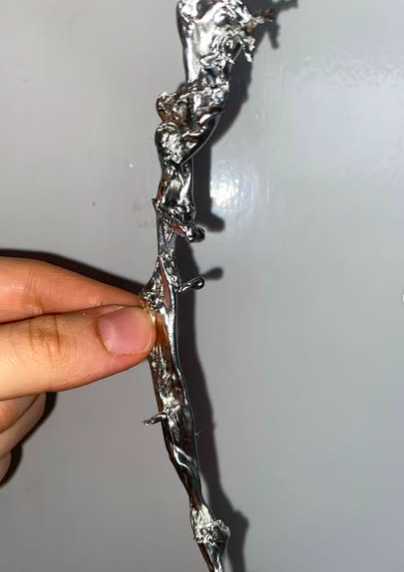eine hand die einen abstrakten zinnguss in die kamera hält.