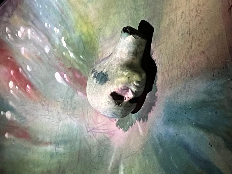 Eine Büste auf der Leinwand, leicht grün, umgeben von fließenden Farben.