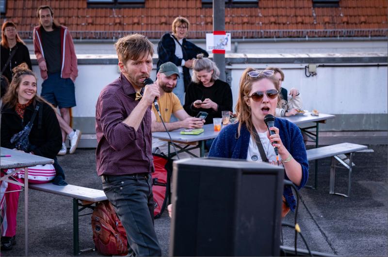 People singing karaoke outdoors in a public setting.