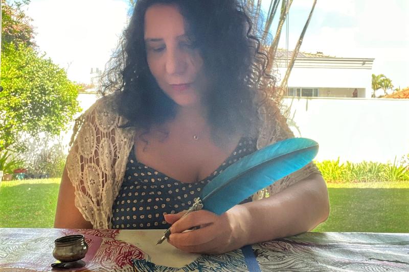 Mirela Fioresy drawing on a canvas with a dip pen.
