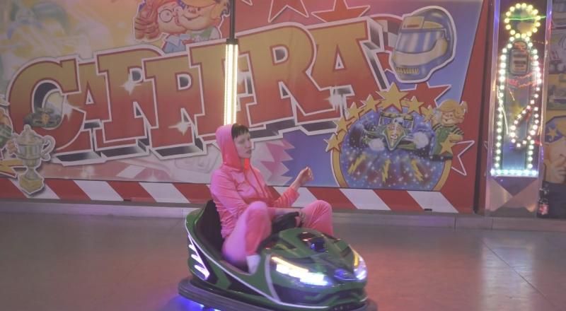 Performerin sitzt in einem Auto im Autoscooter in einem Freizeitpark