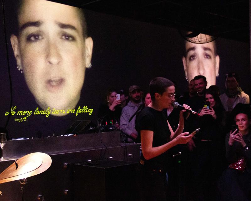 Performance by Mina Amiri Kalvøy in front of a video art work by the same artist.