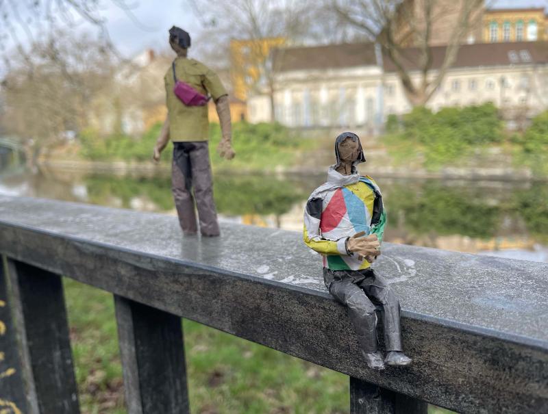 Paper figures are sitting on the edge of a canal in Berlin.