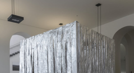a bright, minimalist room with high ceilings and arched doorways. The surface appears textured and slightly torn in places, catching and diffusing the light
