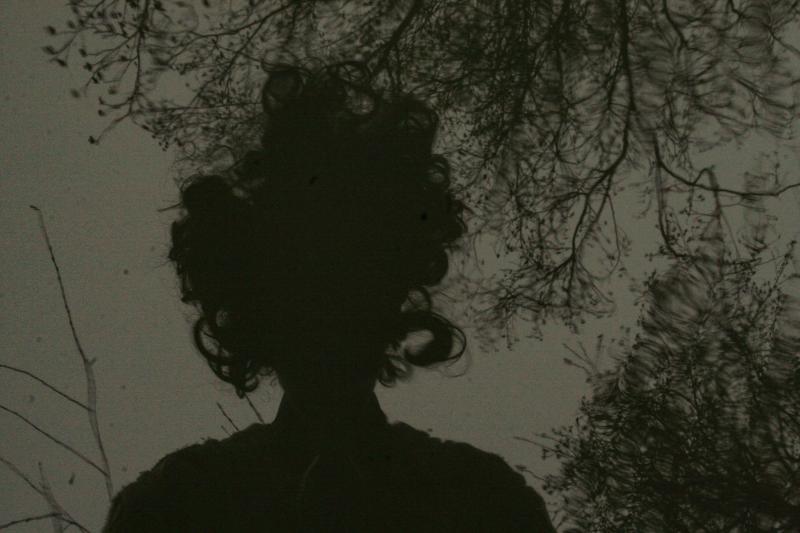 Die Silhouette einer Frau, die sich zusammen mit Bäumen im Wasser spiegelt.
