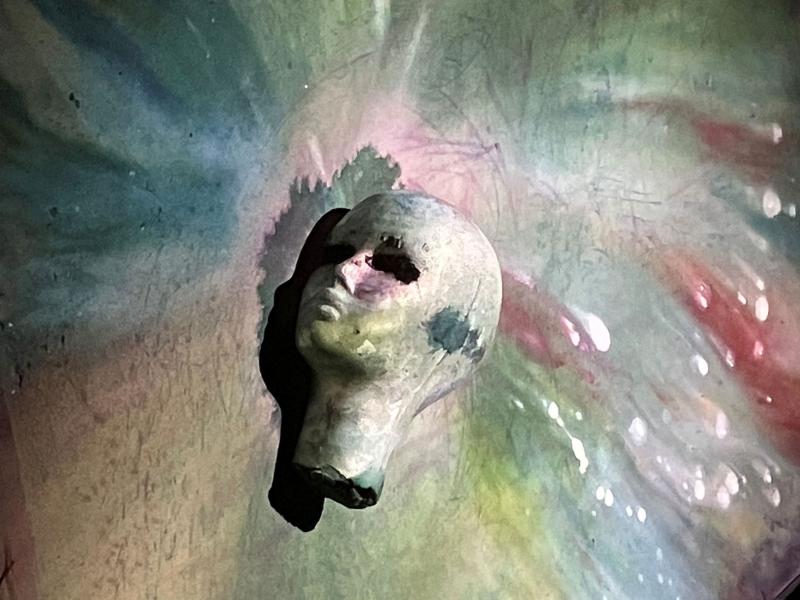 Eine Büste auf der Leinwand, leicht grün, umgeben von fließenden Farben.